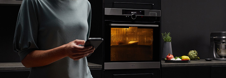 Woman using My Electrolux Kitchen app with oven